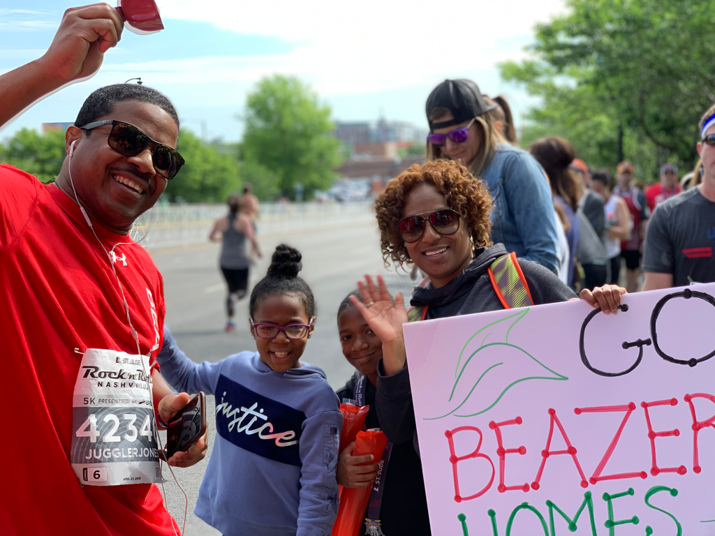 Beazer employee and his family holding a poster cheering on runners during a race